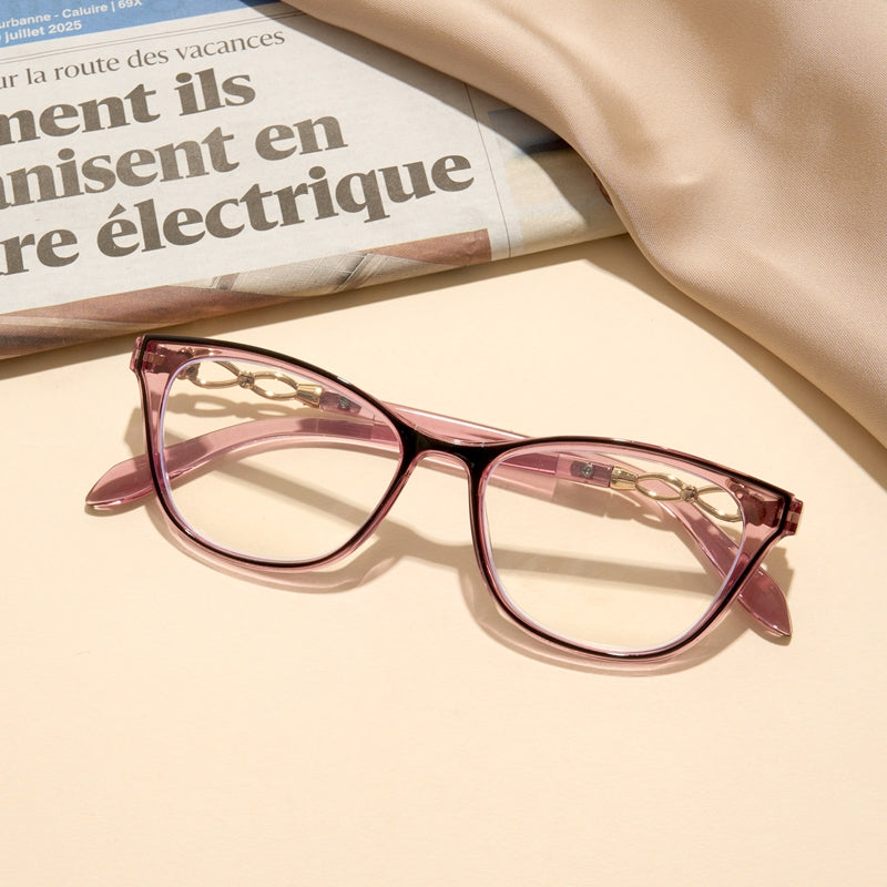 Pink cat-eye glasses on a newspaper with a beige background