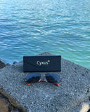 Cyxus sunglasses P1021 and case on a rock with water in the background