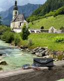 Cyxus sunglasses P1021 and case on a wooden ledge with a scenic background of a church, river, and mountains.