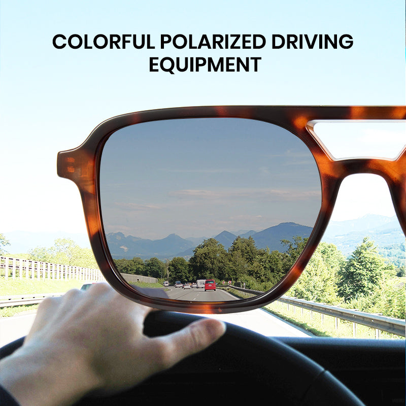 Sunglasses held up to a car windshield with a scenic road and mountains in the background