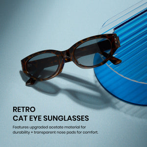 Retro cat-eye sunglasses with a brown tortoiseshell acetate frame and dark tinted lenses, displayed on a light blue textured surface next to a translucent blue ribbed prop. 