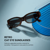 Retro cat-eye sunglasses with a brown tortoiseshell acetate frame and dark tinted lenses, displayed on a light blue textured surface next to a translucent blue ribbed prop. 