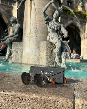 Sunglasses P1021 and case with Cyxus logo in front of a fountain